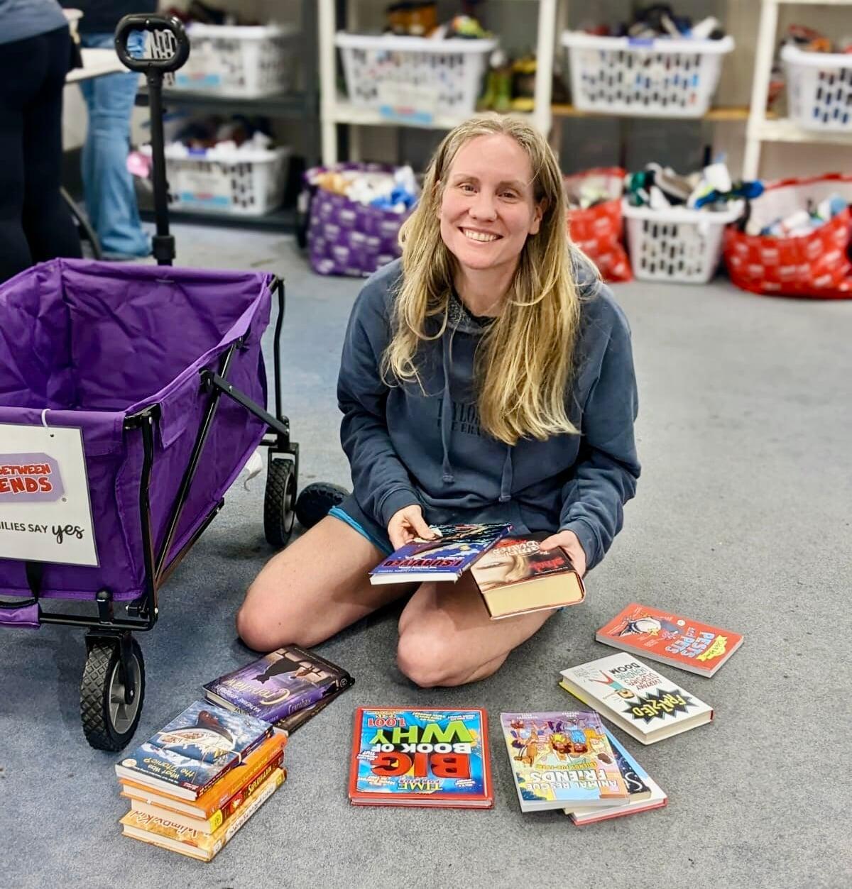 A smiling Team Member stands behind a rack of toddler girl's clothing at the sale.